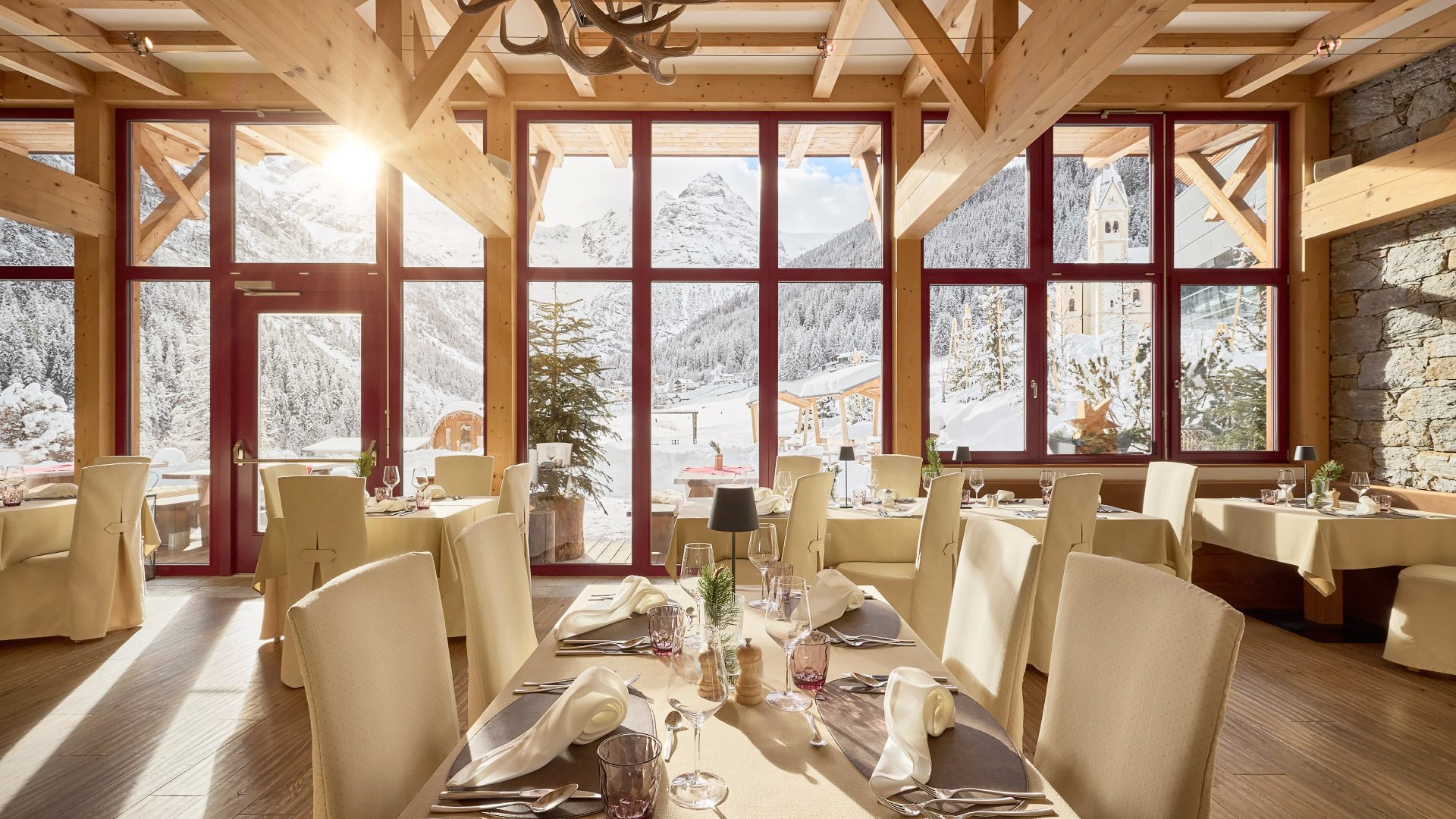 Elegant dining area within Hotel Bella Vista in South Tyrol, featuring large windows that fill the room with sunlight and offer views of the snow-covered Alpine landscape.