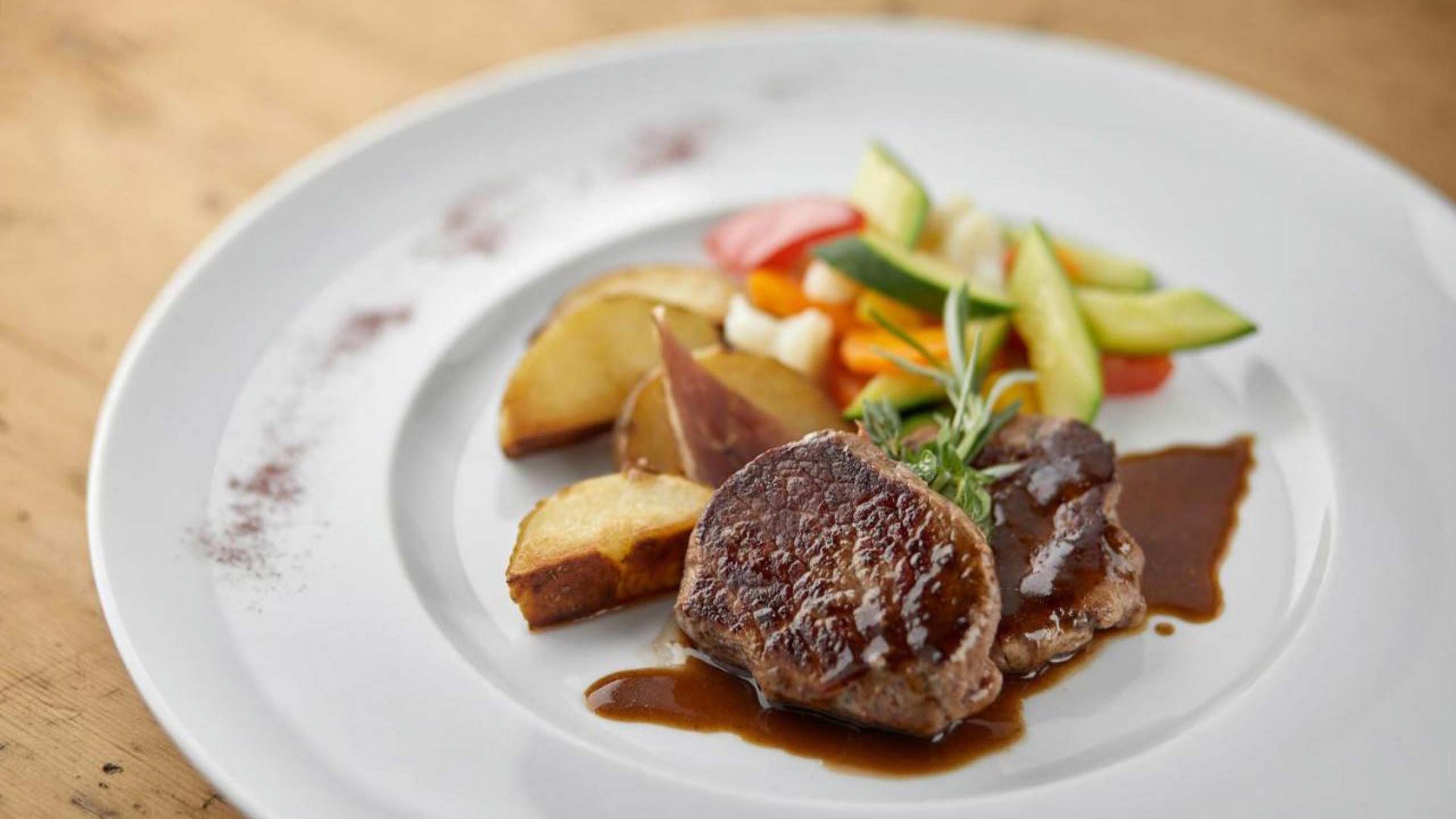 Gourmet-Hauptgericht im Hotel Bella Vista, fein präsentiertes Steak mit einer Seite von frischem Gemüse und Kräuterbutter.