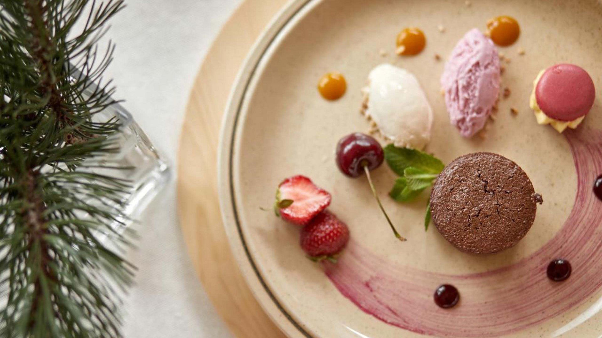 Kunstvoll dekoriertes Dessert mit einer Auswahl an Eiskugeln und frischen Früchten, serviert auf einer Keramikplatte im Hotel Bella Vista.