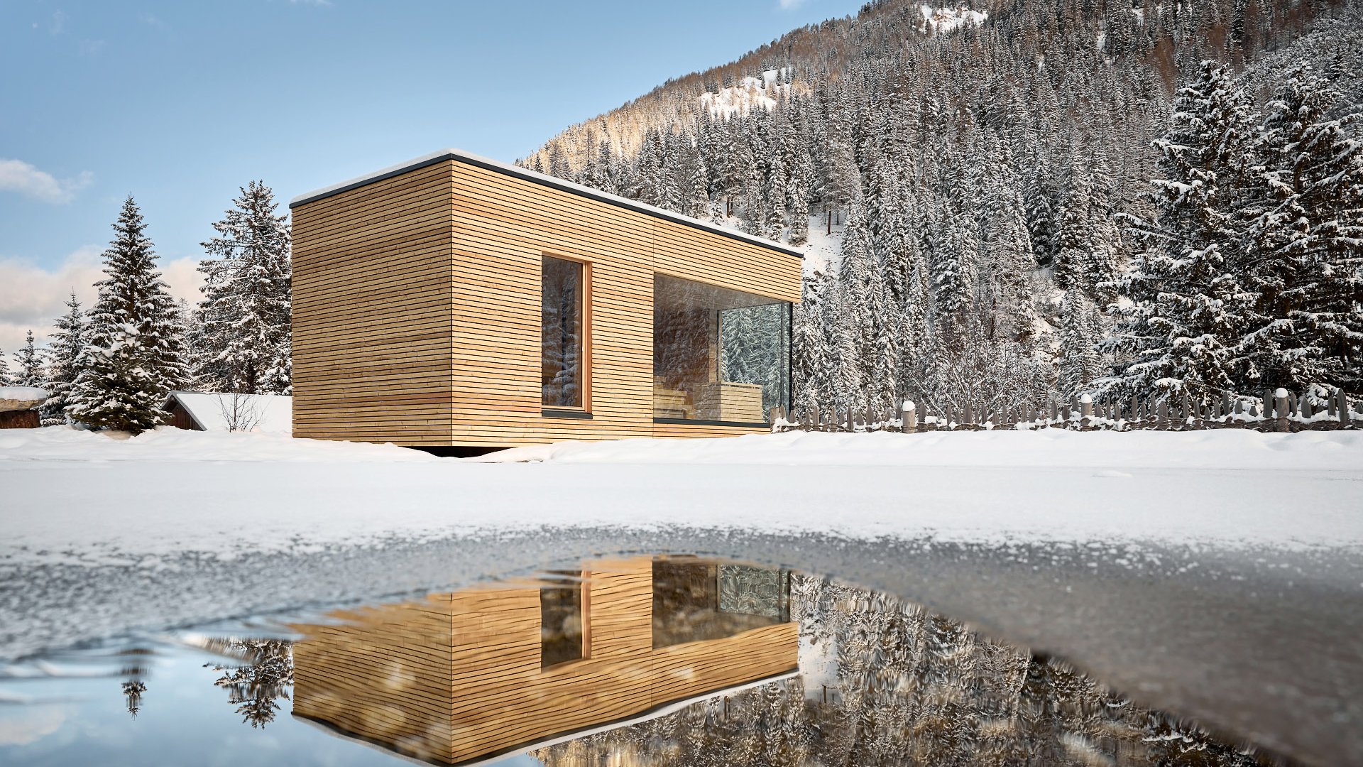 Contemporary designed outdoor sauna of the wellness area with distinctive wooden cladding, reflected on the water surface in front of a snow-covered forest backdrop.