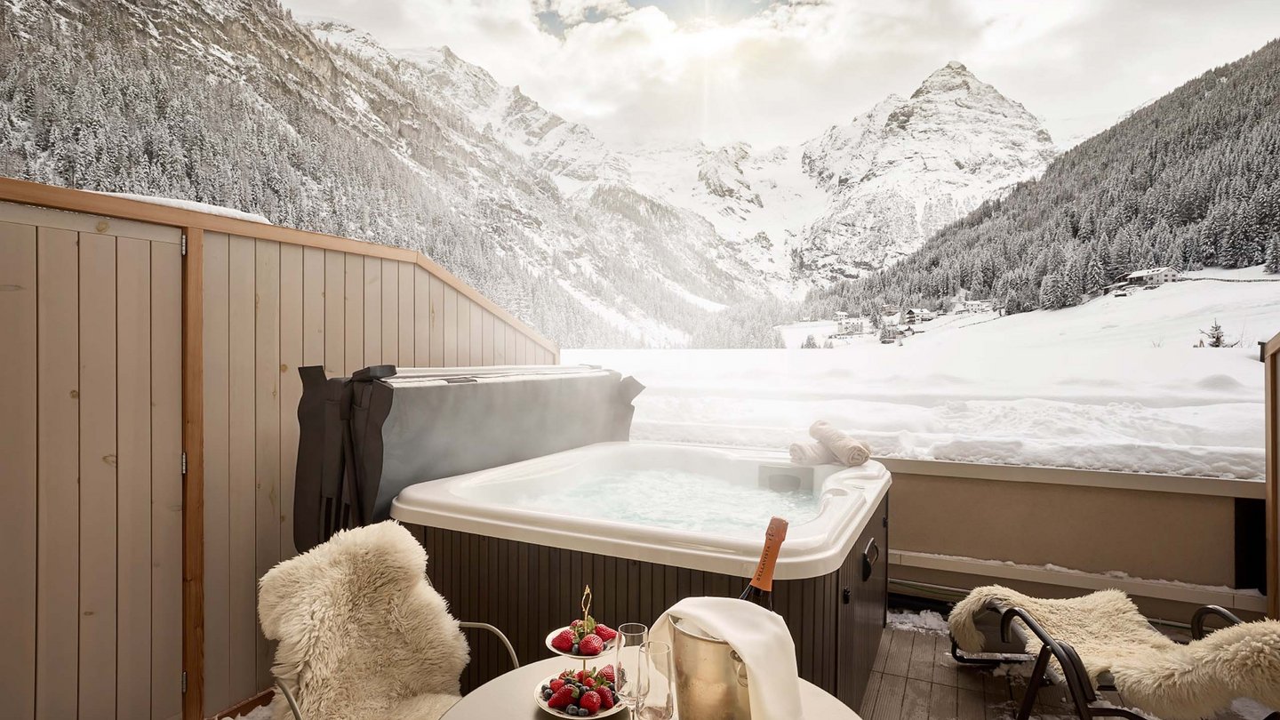 Winterliche Entspannung im Whirlpool des Hotel Bella Vista, mit Blick auf die verschneiten Alpengipfel und bereitgestellten Snacks.